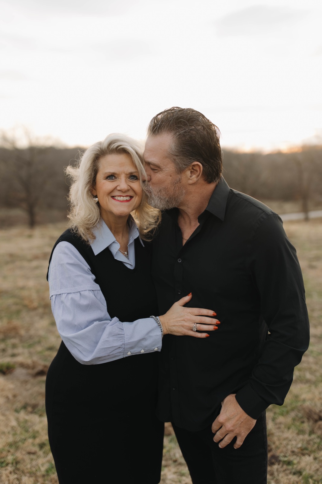 Euel kissing Marsha on the forehead in a winter field.
